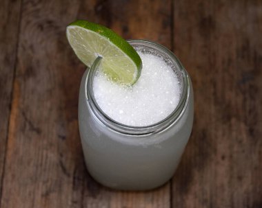 Tahta bir masada bir dilim limonata ile doğal bir limonatanın en üst görüntüsü.