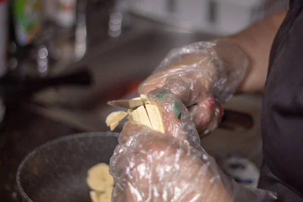 Hands in transparent gloves cutting a banana into small slices