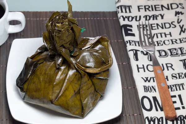 Kolombiyalı tamale, peçete, çatal ve bir fincan kahveyle geleneksel kahvaltı.