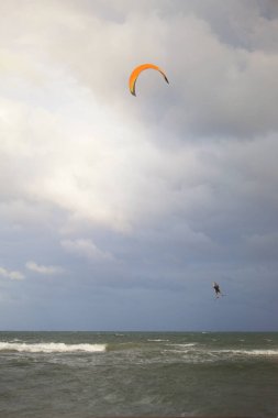 Arka planda bulutlu bir gökyüzü ile tanınmayan yetişkin bir adam uçurtması