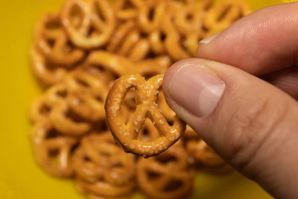 White Hand Foreground Holding Small Pretzel Group Out Focus Pretzels — Stock Photo, Image