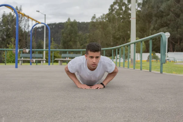 Latin man doing push-ups in a park on a sunny day
