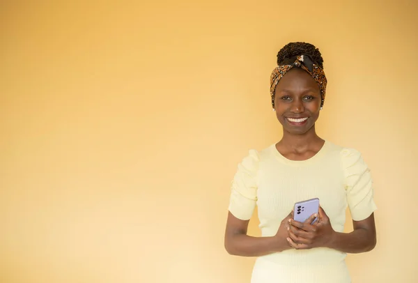 frontal portrait of a young woman smilling and looking at camera with a smartphone in her hands