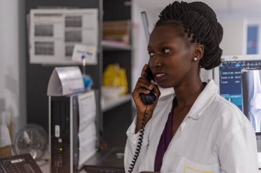 Hastanedeki telefonda konuşan sağlık memurunun yakın çekim görüntüsü.