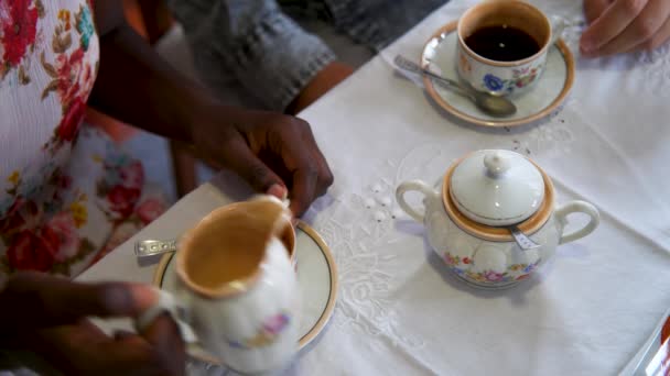 在不同种族的年轻夫妇的密切合作下 他们用一种带有花纹的老式瓷杯 准备并饮用了一杯加奶和糖的咖啡 — 图库视频影像