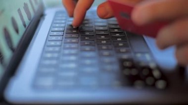 Genç adam bilgisayarını bankamatik ya da kredi kartıyla online alışveriş yapıyor. Çevrimiçi bankacılık kullanımı.