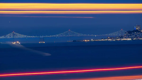 Bay Bridge in the Distance with long exposure traffic lights in foreground in the night with speed blur motion fast line streaks in red and yellow.