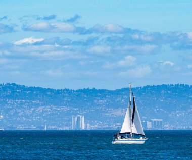 Bright blue water, sailboat mid day scenic view.