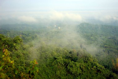 Bukit Biru Çenggarong Tepesi 'nin doğal manzarası. Yeşil ormanlar, açık mavi gökyüzü, sis, ağaçlar ve çok güzel binalar..