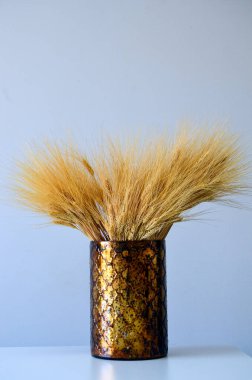 Beyaz masa, ön görüş, minimalizm kavramı üzerinde kahverengi metalik vazoda izole buket. 