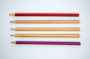  Beyaz arka planda renkli uzun kalemler. Üst manzara, izole ahşap, kırmızı ve mor kalemler..