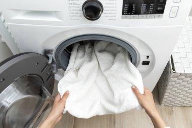 Çamaşır odasında çamaşır makinesinden temiz havlu alan kadın elleri.