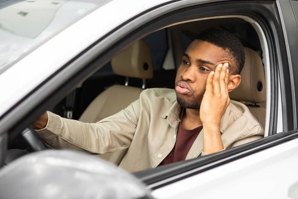 Stressed man sitting in the drivers seat of a car looks into the windshield and thinks. High quality photo