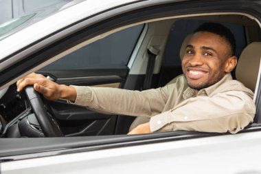 Yakışıklı siyah adam arabasını sürüyor ve kameraya gülümsüyor. Yüksek kalite fotoğraf