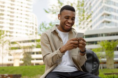 Sokakta kulaklıkla ve cep telefonuyla şarkı dinleyen mutlu bir Afro-Amerikan erkeği. Yüksek kalite fotoğraf
