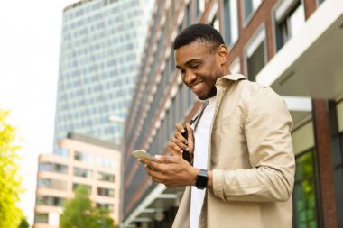 Şehrin arka planında akıllı telefon kullanan Afro-Amerikalı bir adam var. Yüksek kalite fotoğraf