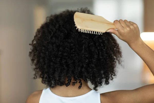 Rear view of a lady combing her hair with a wooden comb. Selective Focus. High quality photo