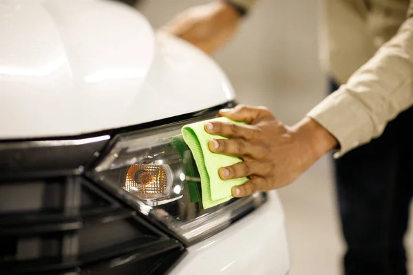 Headlight cleaning. A man wipes the headlights of a car with a soft cloth. High quality photo