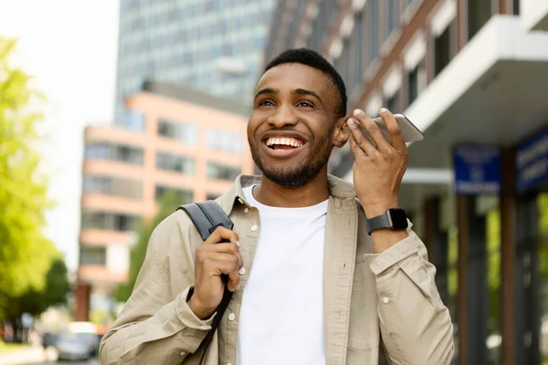 A black man listens to a voice message on a loudspeaker phone, walks down the street. High quality photo