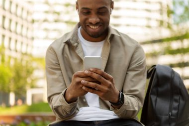 Zeki telefondan mesaj gönderen mutlu genç siyahi adam, yakın plan, bulanık geçmiş. Yüksek kalite fotoğraf