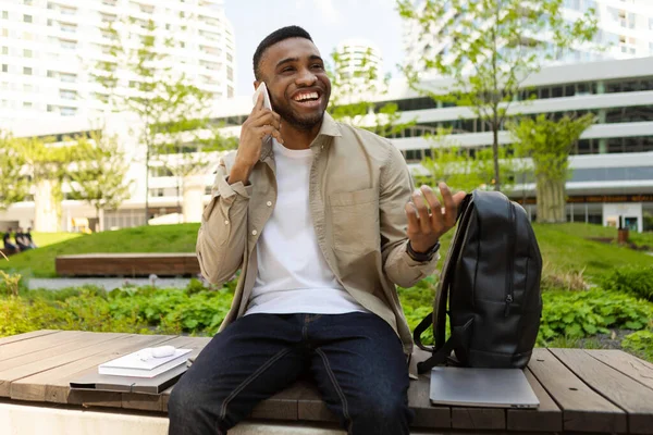 Young man laughs while talking on the phone on the street.. High quality photo