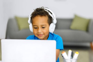 Smiling african american schoolboy doing homework while sitting at table at home. High quality photo