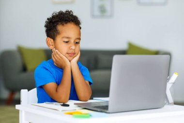 Portrait of a black preschooler who teaches Internet lessons, holds his head with his hands, close-up. High quality photo