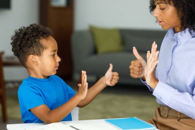 A smart boy counts on his fingers, studies with a private teacher in the office, a child learns numbers and how to count, sits at a table with a tutor. High quality photo