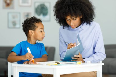A young teacher helps a boy in elementary school lessons, shows a lesson in a book. High quality photo