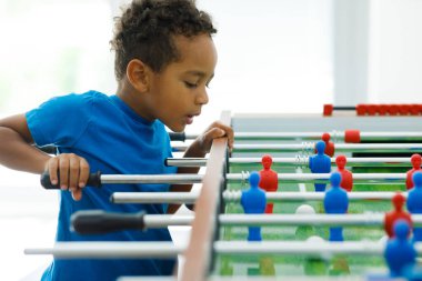 An African boy is having fun playing table football in a childrens play entertainment center. Hobby and leisure. High quality photo