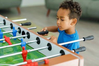 An African boy is having fun playing table football in a childrens play entertainment center. Hobby and leisure. High quality photo