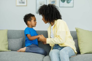 Angry young mother arguing with little son who is misbehaving by being stubborn while talking to him. The concept of the conflict of parents and children. High quality photo