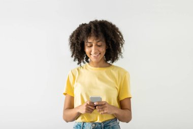 Beyaz stüdyonun arka planında dikilirken arkadaşlarıyla sohbet etmek için akıllı telefon kullanan neşeli zenci kadının portresi, kopyalama alanı. Yüksek kalite fotoğraf