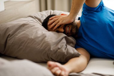 Milenyum adamı, modern yatak odasında yatağında yatarken uykusuzluk ve baş ağrısı semptomlarıyla kafasına dokunuyor. Yüksek kalite fotoğraf