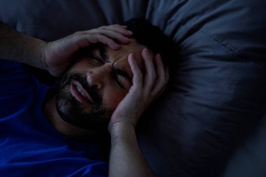 Sakallı genç adam baş ağrısıyla uyanıyor, kafasına dokunuyor, migreni tutuyor ya da akşamdan kalma, fotokopi çekiyor. Yüksek kalite fotoğraf