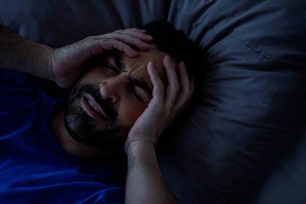 Бородатый молодой человек просыпается с головной болью, трогает голову, у него мигрень или похмелье, скопируйте пространство. Высокое качество фото