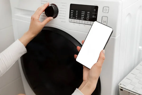女人按下洗衣机的按钮 手里拿着电话 高质量的照片 — 图库照片
