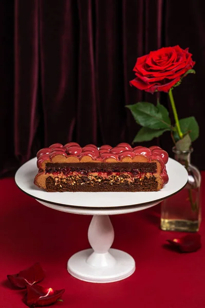 Mousse cake with red mirror icing. Cutaway cake: chocolate sponge cake, crunchy layer, cherry confit, cherry cream, chocolate mousse.