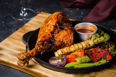 Fırında pişmiş hindi budu, domates sosu ve kızartma tavasında ızgara sebze. Restoran yemeği.