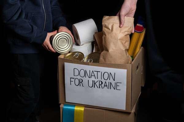 Добровольцы собирают пожертвования для украинцев по всему миру. Пожертвования для людей из Украины. Пожертвования, еда, благотворительность для военных беженцев. Заботиться о людях. Руки добровольцев