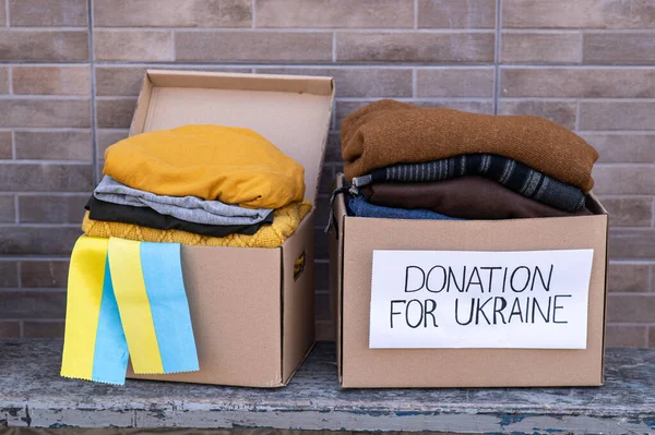 Boxes with humanitarian aid for Ukrainian refugees on the street. Ukrainian symbols, boxes with clothes