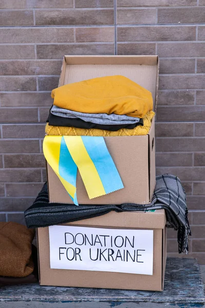 Boxes with humanitarian aid for Ukrainian refugees on the street. Ukrainian symbols, boxes with clothes