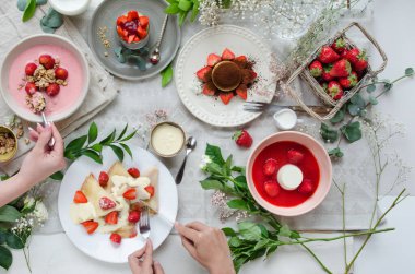 İçinde çilek tabakları olan bir masa - tiramisu, bardakta cheesecake, yoğurtlu granola, krep ve çilekli panna kota. Yaz çileği menüsü, lezzetli kahvaltı. Yan manzara, tasarım afişi..