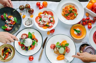 Tabakların çeşitleri masada. Restoranda domates menüsü, domates çorbası, bufalo mozzarella ve pesto ile domates karışımı fırında fileto, domates soslu makarna, domates salatası. Restoran menüsü. İtalyan mutfağı. Üst görünüm