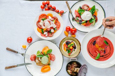 Tabakların çeşitleri masada. Restoranda domates menüsü, domates çorbası, bufalo mozzarella ve pesto ile domates karışımı fırında fileto, domates soslu makarna, domates salatası. Metin için yer