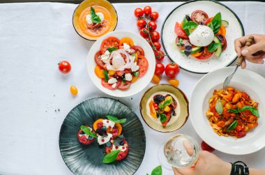 Tabakların çeşitleri masada. Masada çeşitli aperatifler ve antipasti. Restoranda domates menüsü, domates çorbası, bufalo mozzarella ve pesto ile domates karışımı, fırında domates soslu domuz filetosu, domates soslu makarna, domates salatası. Yer