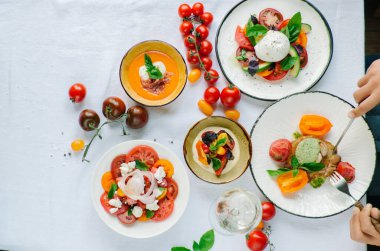 Tabakların çeşitleri masada. Masada çeşitli aperatifler ve antipasti. Restoranda domates menüsü, domates çorbası, bufalo mozzarella ve pesto ile domates karışımı, fırında domates soslu domuz filetosu, domates soslu makarna, domates salatası. Yer
