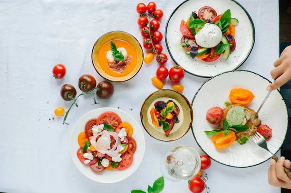 Tabakların çeşitleri masada. Masada çeşitli aperatifler ve antipasti. Restoranda domates menüsü, domates çorbası, bufalo mozzarella ve pesto ile domates karışımı, fırında domates soslu domuz filetosu, domates soslu makarna, domates salatası. Yer