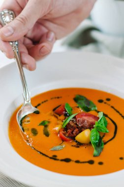 Bitkilerle lezzetli kremalı domates çorbası. Yaz sarısı domates çorbası. Kaşıkla çorba tatma