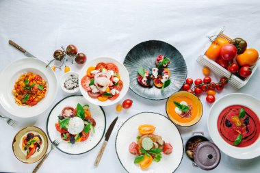 Tabakların çeşitleri masada. Restoranda domates menüsü, domates çorbası, bufalo mozzarella ve pesto ile domates karışımı fırında fileto, domates soslu makarna, domates salatası. Metin için yer